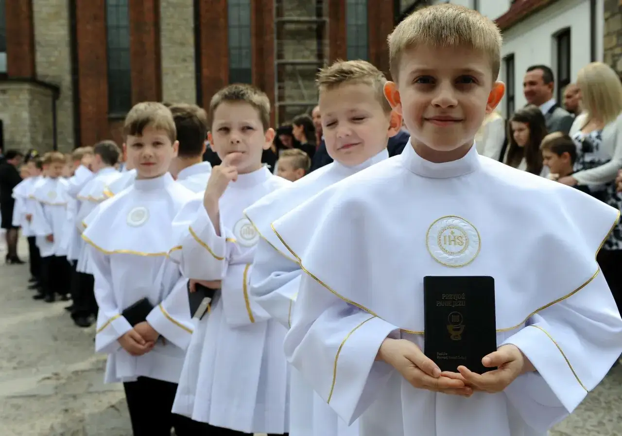 Chłopcy w białych albach, gotowi do komunii. W której klasie jest komunia? To ważny dzień dla tych młodych ludzi.
