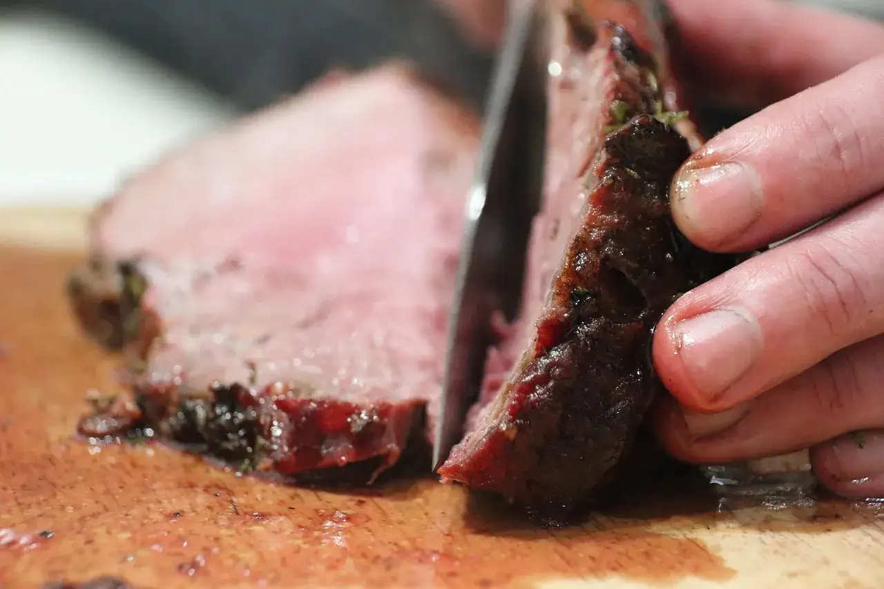 Saftiges Flank Steak wird auf einem Holzbrett in Scheiben geschnitten.