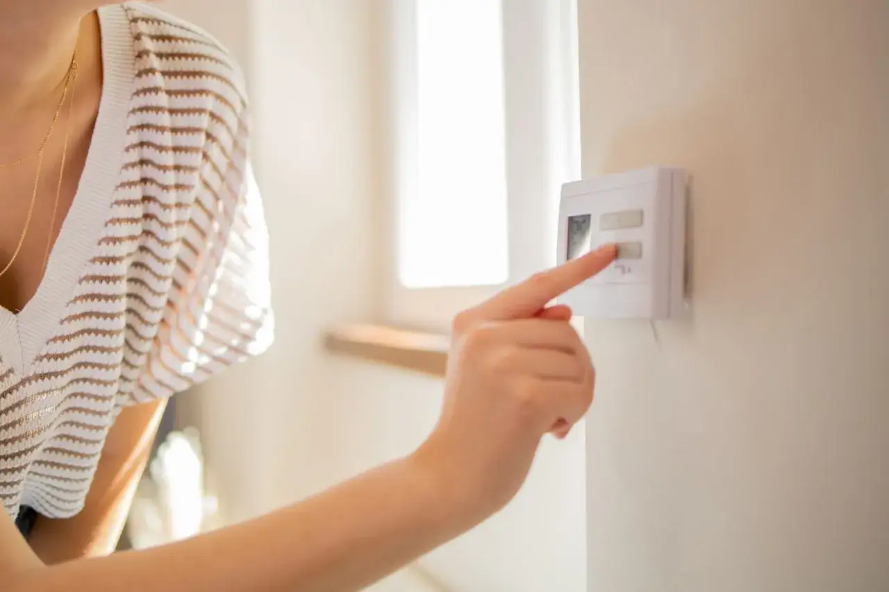 Mano ajustando el termostato. ¡Uf, 26 grados es calor!
