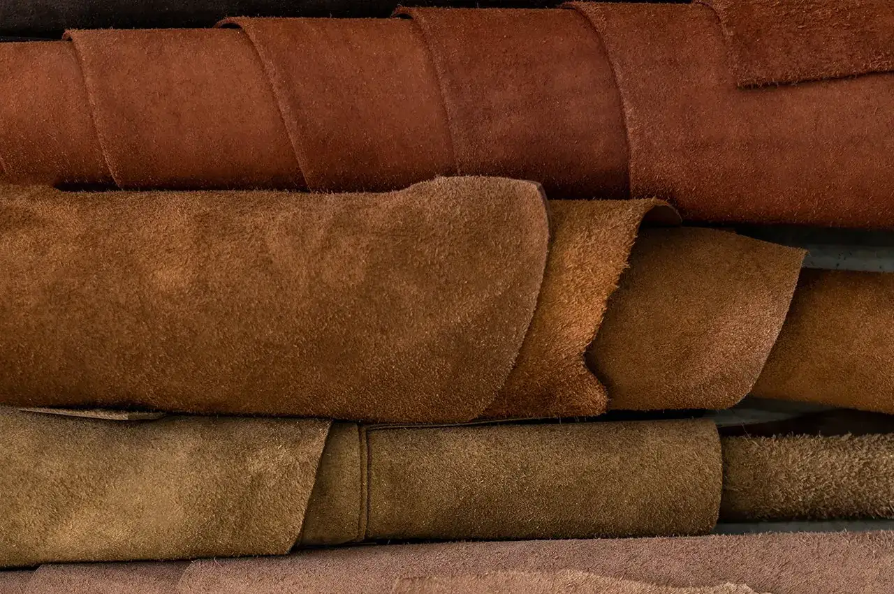Superposition de rouleaux de cuir aux teintes brunes et ocres, évoquant la richesse et la qualité cuir.