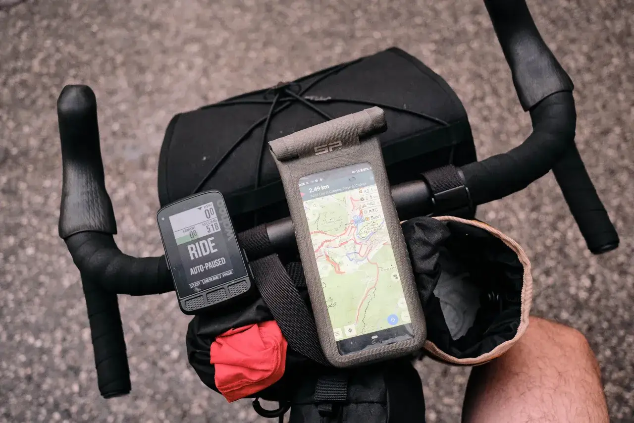 Rowerzysta przygotowuje się do wyprawy, na kierownicy zamontowany jest licznik Wahoo i smartfon z mapą, gotowy do nawigacji.