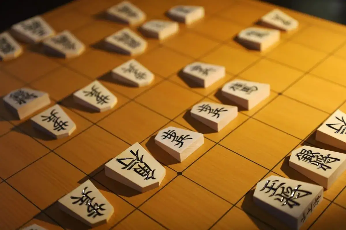 Drewniane pionki z japońskimi znakami na planszy do gry. Japońska gra planszowa Shogi w zbliżeniu.