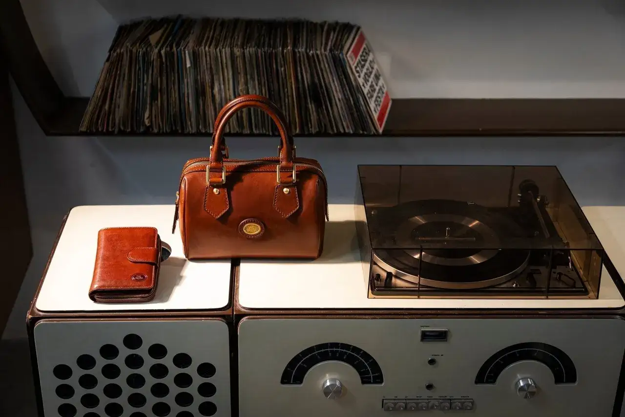 Borsa in pelle marrone, portafoglio e giradischi vintage. Scopri come pulire una borsa di pelle per mantenerla sempre al top.