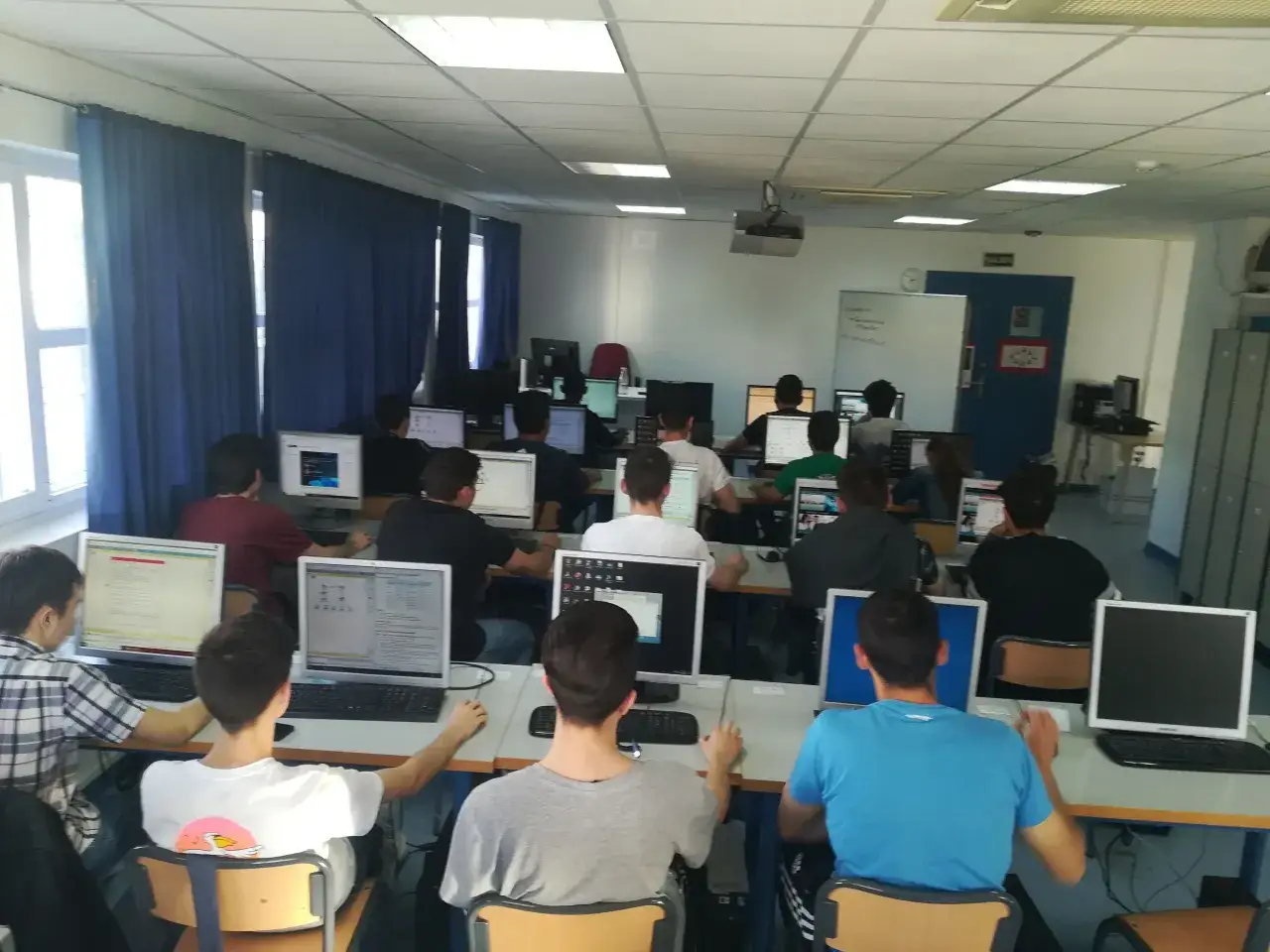 Estudiantes de grado medio informática concentrados frente a sus ordenadores en un aula.