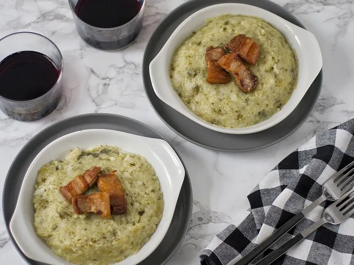 Dos platos de trinxat de la Cerdanya, un plato tradicional catal&aacute;n, servidos con trozos de panceta crujiente.
