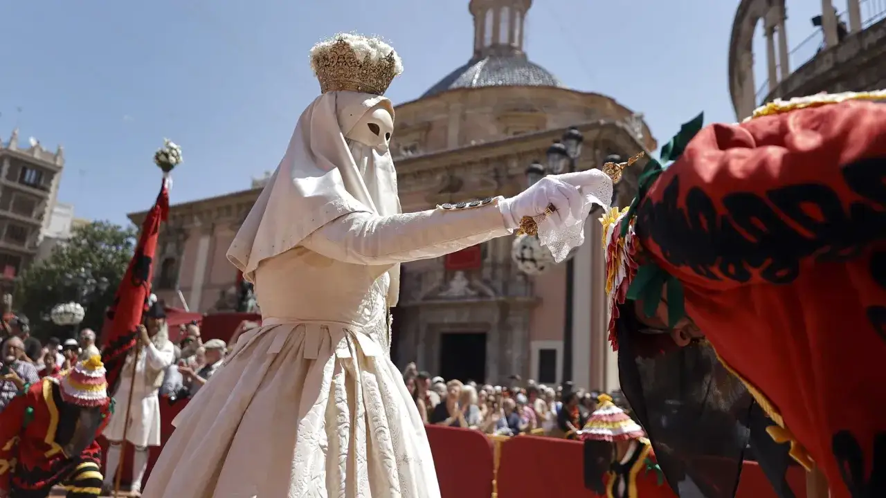 Una figura con corona y máscara blanca, vestida de época, extiende una mano enguantada. Podría ser parte de la celebración del Corpus 2026.