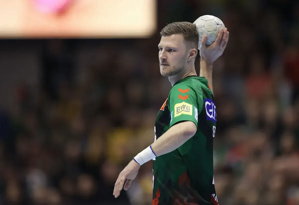 Philipp Weber, szczypiornista w zielonej koszulce, szykuje się do rzutu piłką.