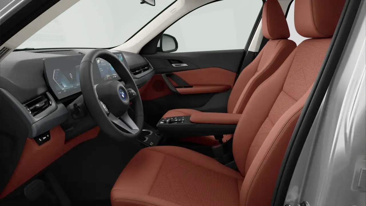 Wnętrze BMW iX1 z brązową tapicerką i nowoczesnym panelem cyfrowym. Sprawdź BMW iX1 cena.