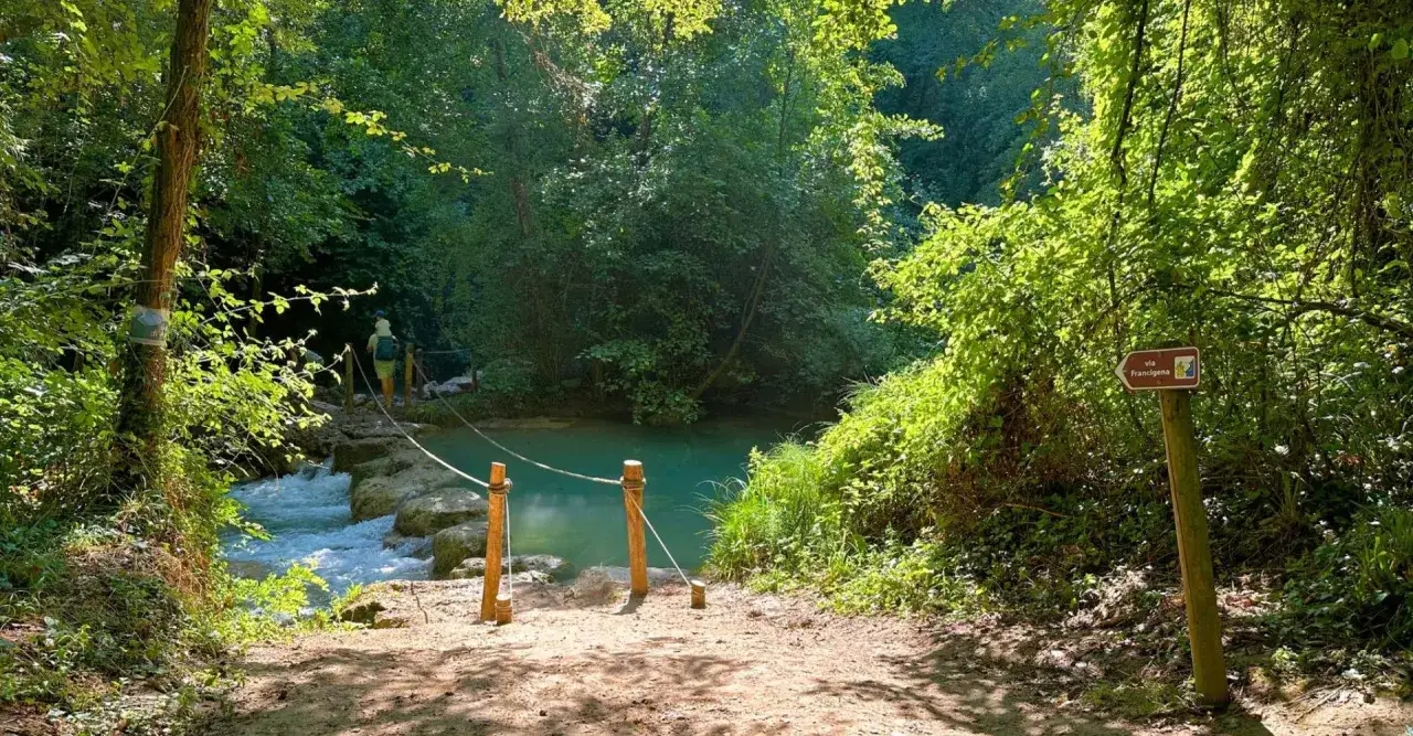 Sentiero per escursioni in Toscana, con un guado su un ruscello e un cartello per la Via Francigena.