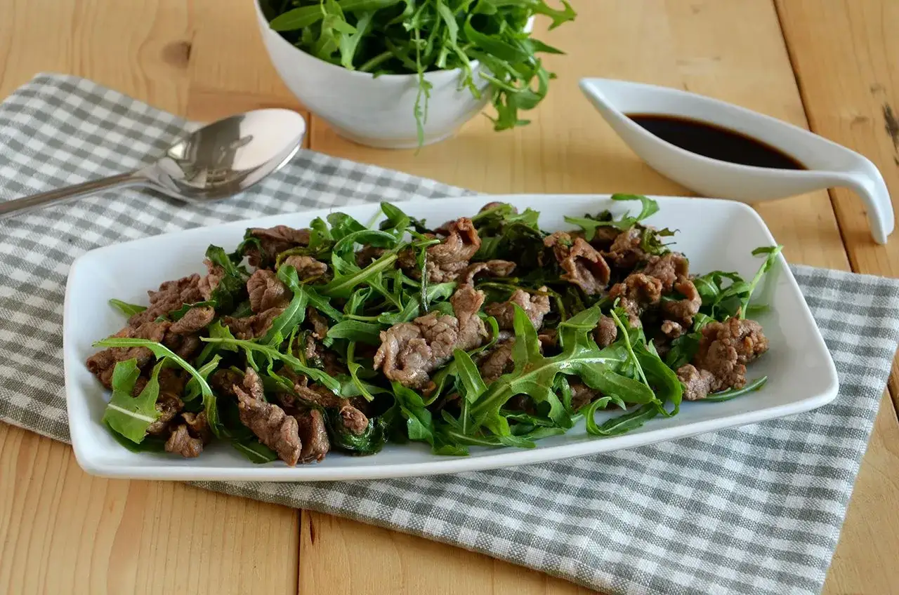 Straccetti di manzo saltati con rucola fresca, un piatto leggero e saporito, pronto per essere gustato.