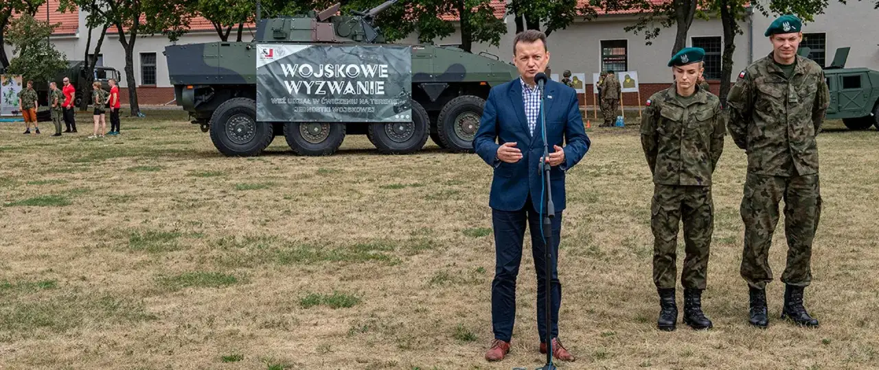 Minister przemawia obok pojazdu wojskowego i żołnierzy. Czy po służbie przygotowawczej można zostać żołnierzem zawodowym?