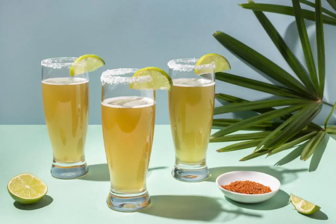 Trois verres de bi&egrave;re avec des bords sal&eacute;s et des quartiers de citron vert, pr&ecirc;ts pour une d&eacute;gustation. El tequito vs desperados, un choix rafra&icirc;chissant.