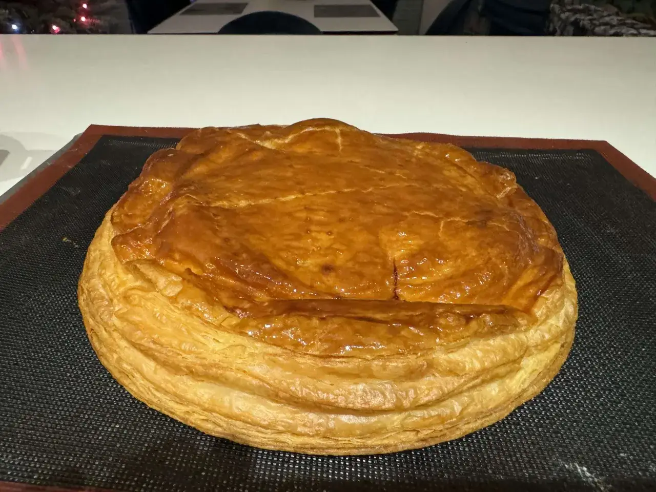 Une galette des rois coco dorée et feuilletée, prête à être dégustée. Son dessus est légèrement craquelé, promettant une texture délicieuse.