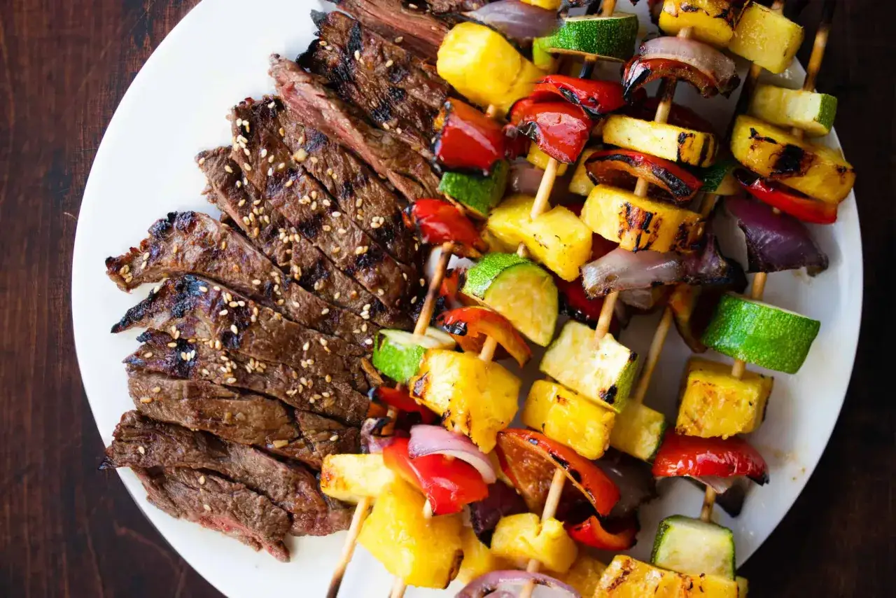 Skivad biff med sesamfr&ouml;n bredvid grillspett med ananas, paprika, zucchini och r&ouml;dl&ouml;k. En h&auml;rlig shish kebab-tallrik.