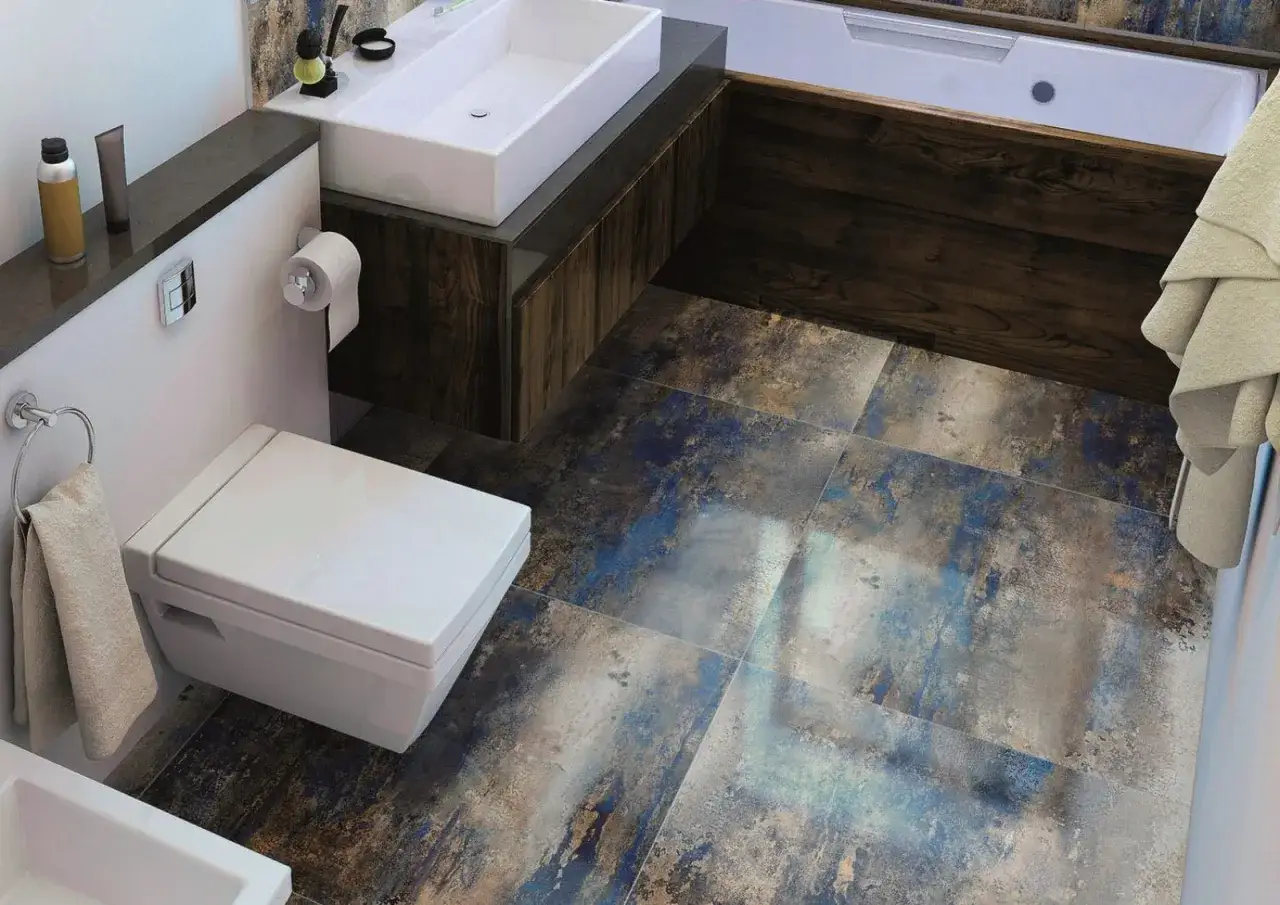Nowoczesna łazienka z wiszącą białą miską WC i umywalką nablatową. Podłoga wyłożona wielkoformatowymi płytkami 60x60 w odcieniach niebieskiego i brązu.
