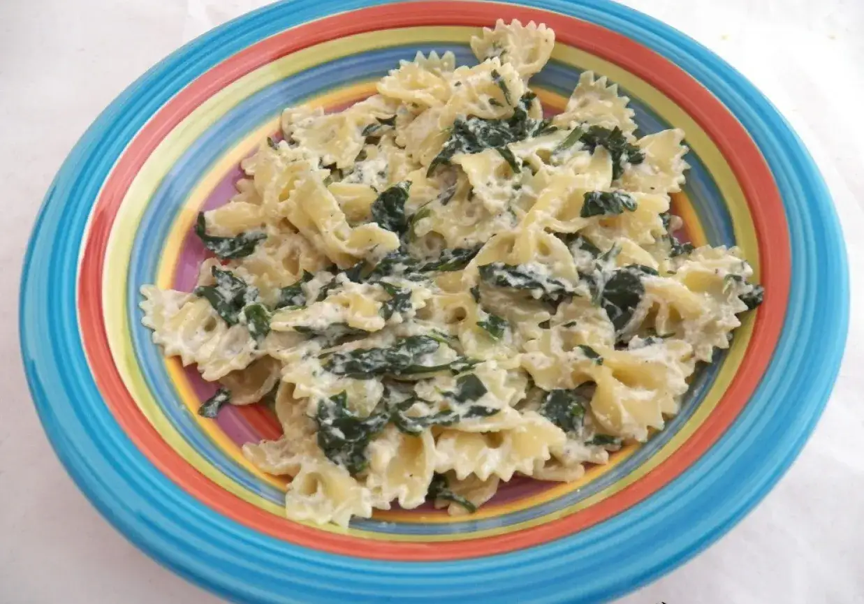 Pyszny makaron farfalle z kremowym sosem na bazie ricotty i szpinaku, podany w kolorowej misce.