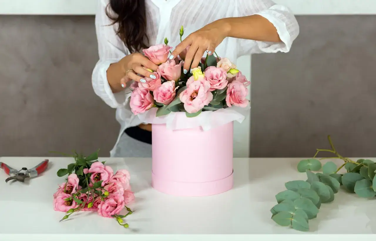 Tworzenie flower boxa: jak zrobić pudełko do flower boxa. Różowe róże i eukaliptus w okrągłym pudełku.