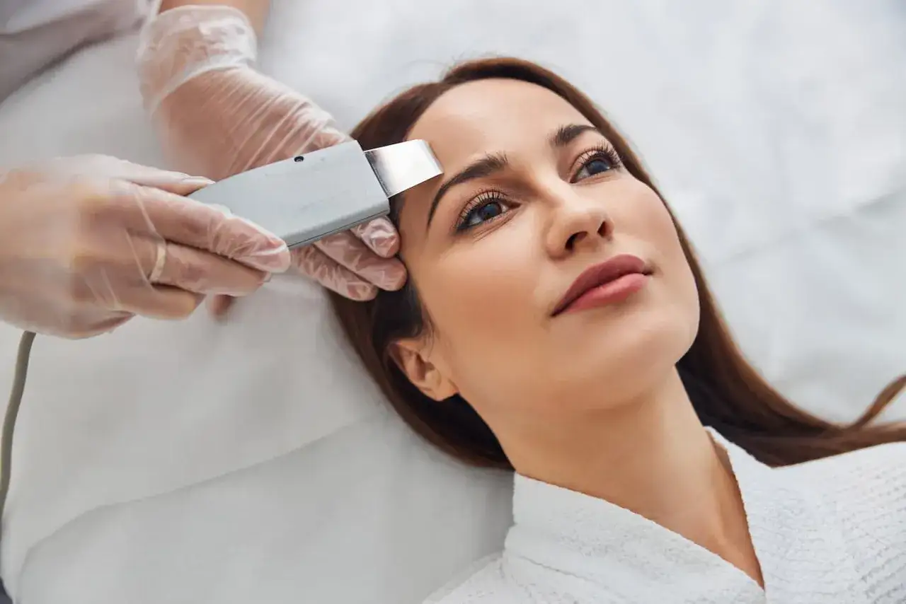 Una cosmet&oacute;loga realiza un peeling ultras&oacute;nico en la frente de una mujer. Este tratamiento de belleza ayuda a renovar la piel.