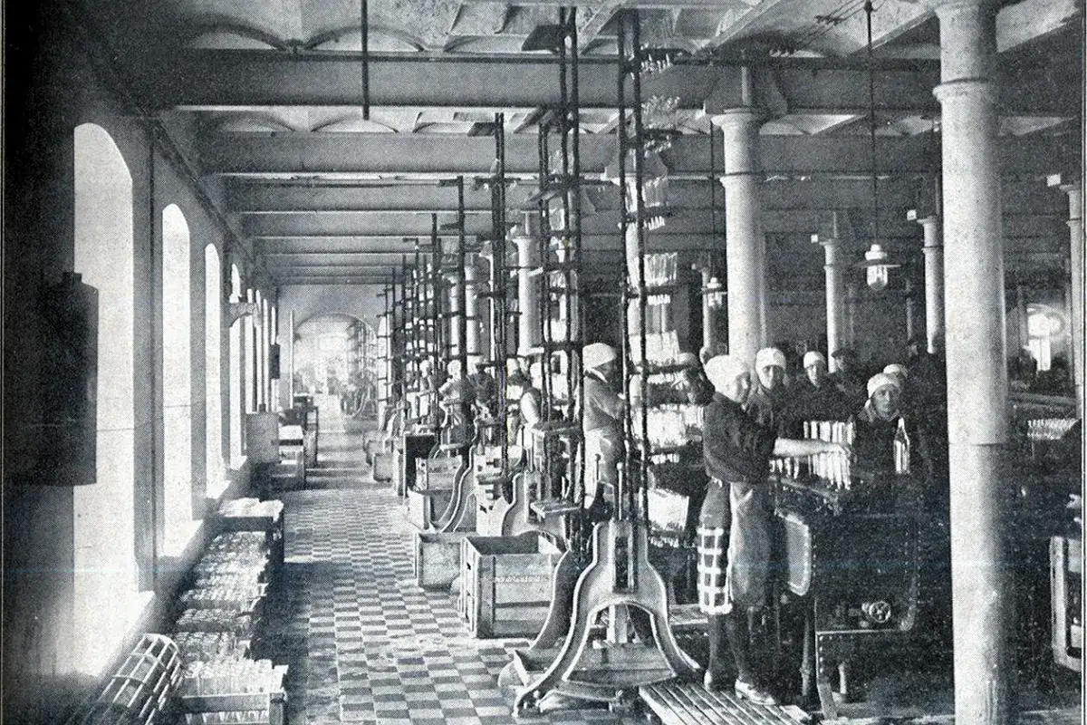 Pracownicy w fabryce butelkują wódkę. To właśnie tutaj zaczyna się historia tego trunku.