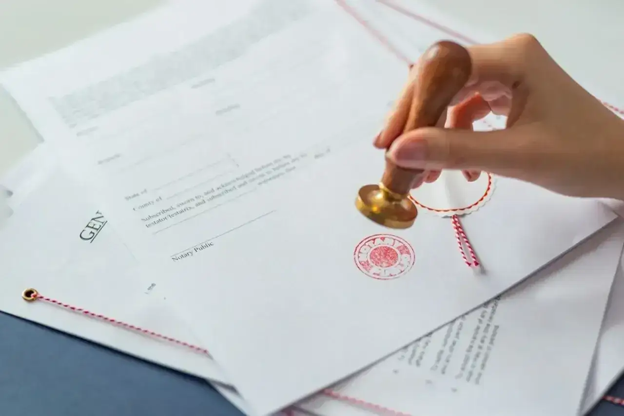 Dłoń z pieczęcią notarialną wykonuje własnoręczne poświadczenie za zgodność z oryginałem na dokumencie.