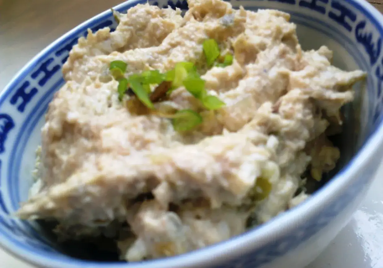 Puszysta pasta z makreli i jajek, udekorowana szczypiorkiem, w miseczce z niebieskim wzorem.