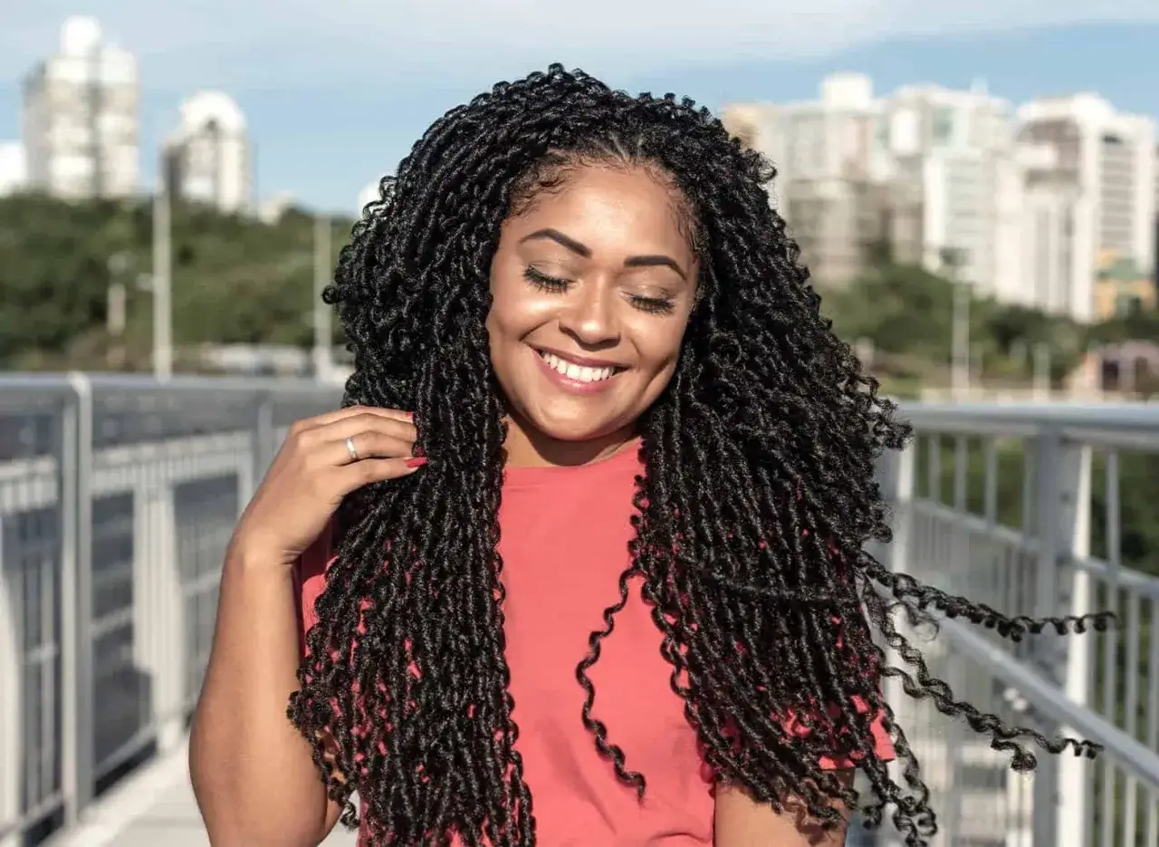 Mujer sonríe con sus espectaculares trenzas africanas, luciendo un estilo moderno y vibrante.