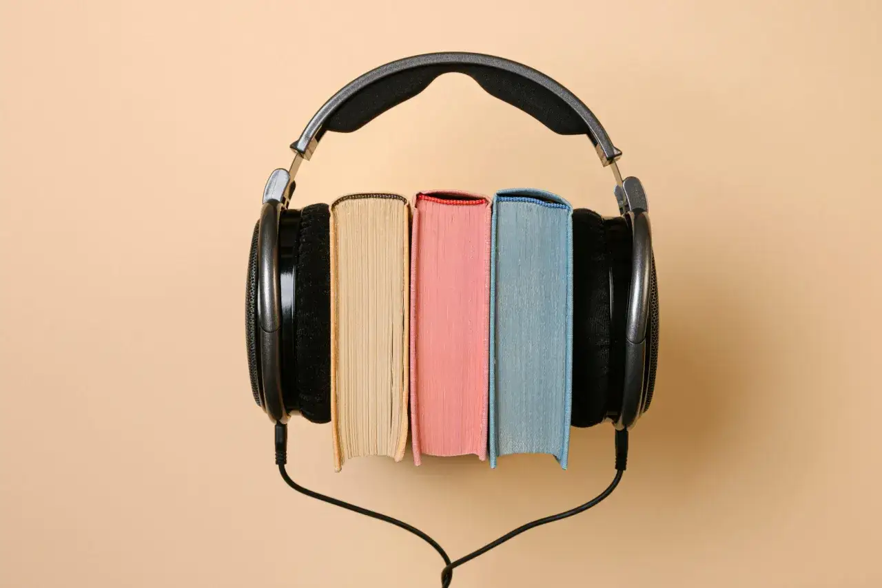 Słuchaj darmowych audiobook&oacute;w po angielsku dla początkujących. Słuchawki na książkach symbolizują naukę przez słuch.
