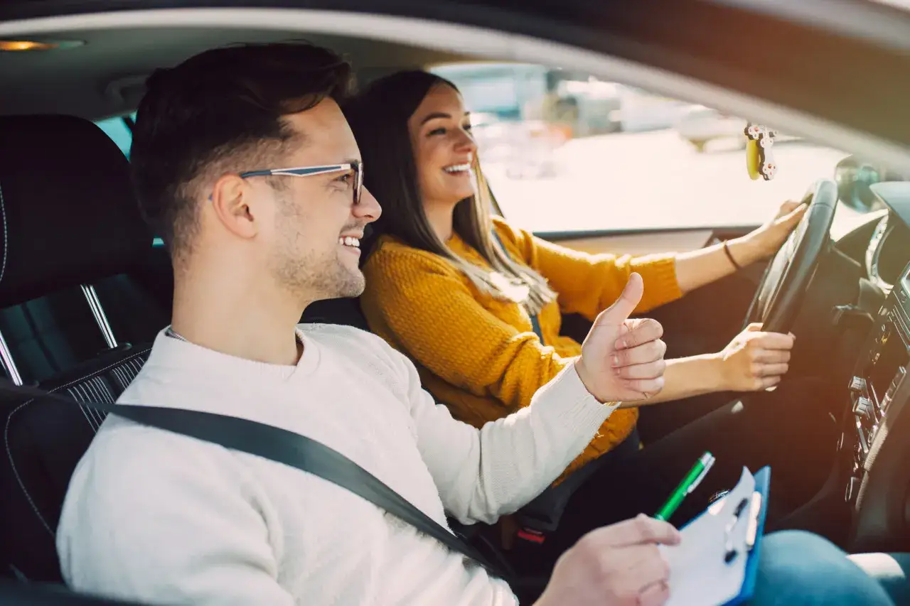 Un moniteur d'auto-&eacute;cole donne son approbation &agrave; une &eacute;l&egrave;ve conductrice. Une sc&egrave;ne de conduite normale, loin de la r&eacute;pression des fraudes auto-&eacute;cole.
