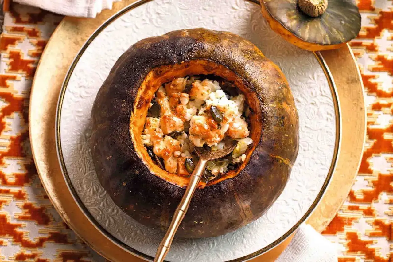 Deliziosa zucca ripiena con riso, cubetti di carne e semi di zucca, pronta per essere gustata.