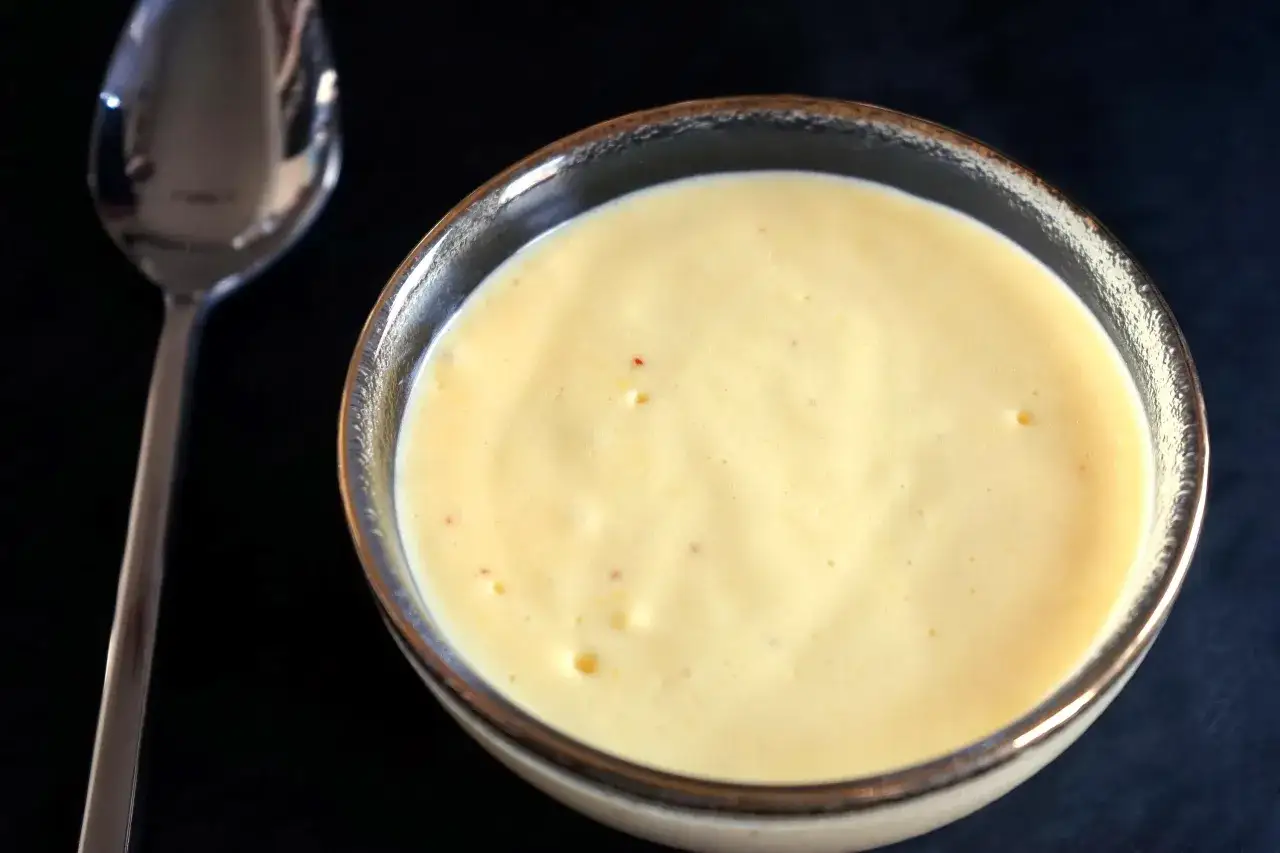 Un bol de sauce hollandaise onctueuse, pr&ecirc;te &agrave; &ecirc;tre d&eacute;gust&eacute;e avec une cuill&egrave;re &agrave; proximit&eacute;.