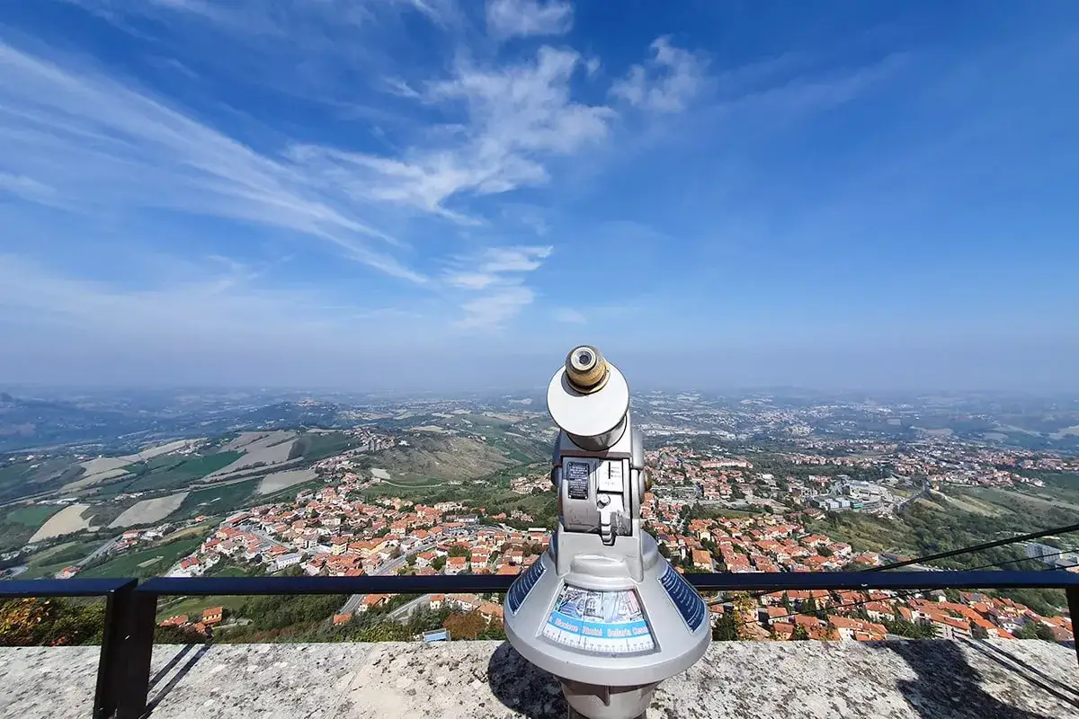 Telescopio pronto per esplorare i panorami mozzafiato, perfetto per i tuoi san marino tours. Vista sulla città e colline sotto un cielo azzurro.