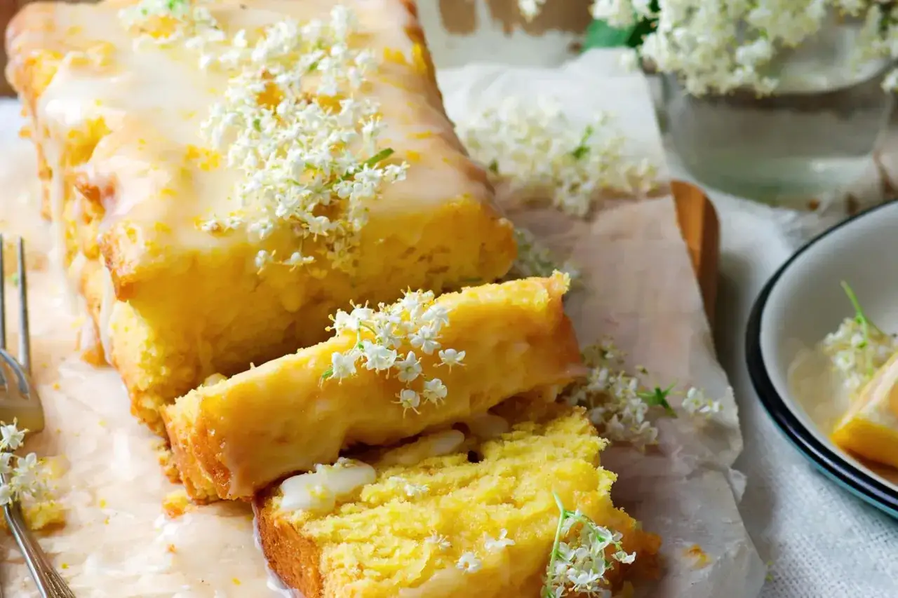 Saftiger veganer Zitronenkuchen mit zarter Glasur und Holunderbl&uuml;ten verziert. Ein Genuss f&uuml;r alle Sinne.