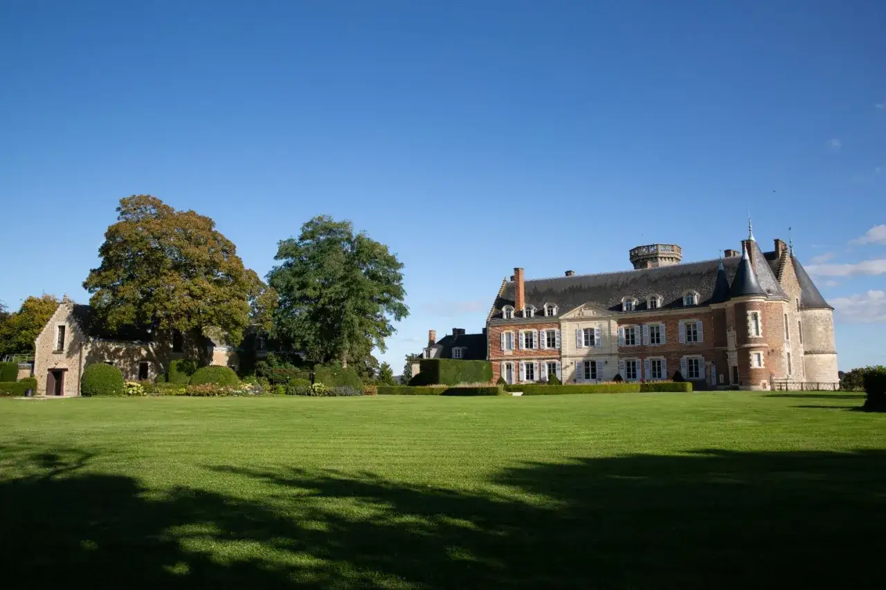 Le ch&acirc;teau de Montmirail, majestueux &eacute;difice de pierre et de brique, se dresse fi&egrave;rement sous un ciel bleu, entour&eacute; d'une pelouse verdoyante et d'arbres aux couleurs d'automne.