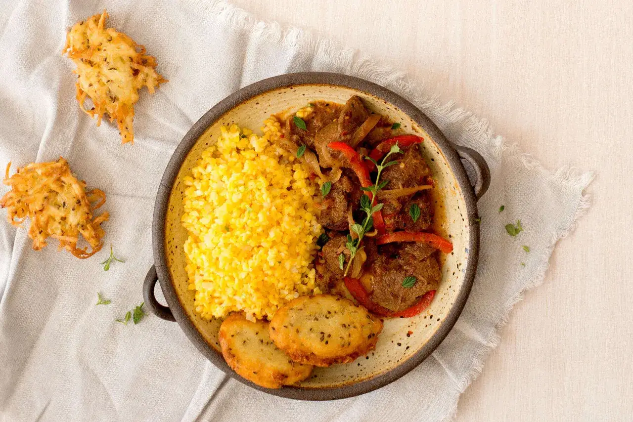 Guiso de carne con pimientos y cebolla, acompa&ntilde;ado de arroz amarillo y tortitas de patata. El tomillo para que sirve, realza el sabor de este plato.