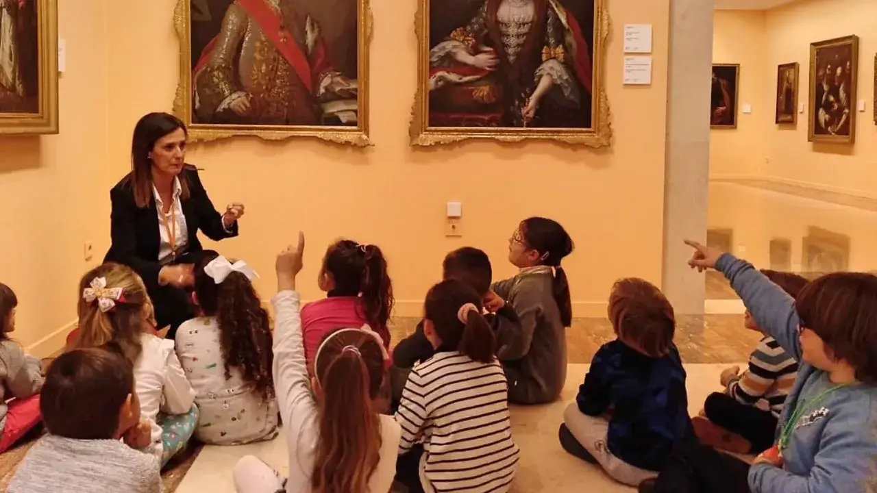 Niños atentos en un museo, aprendiendo sobre arte en el **18 de mayo día de los museos**.