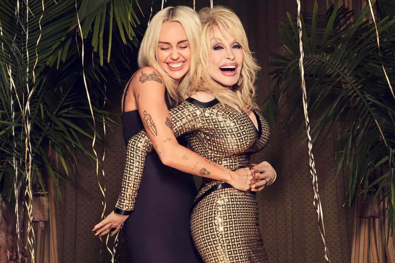 Dolly Parton i Miley Cyrus, dwie ikony muzyki, przytulają się radośnie na tle palm i złotych serpentyn.