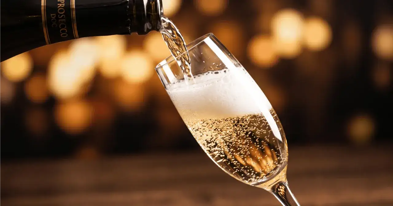 Prosecco, włoskie wino musujące, leje się do kieliszka, tworząc obfitą pianę i bąbelki.