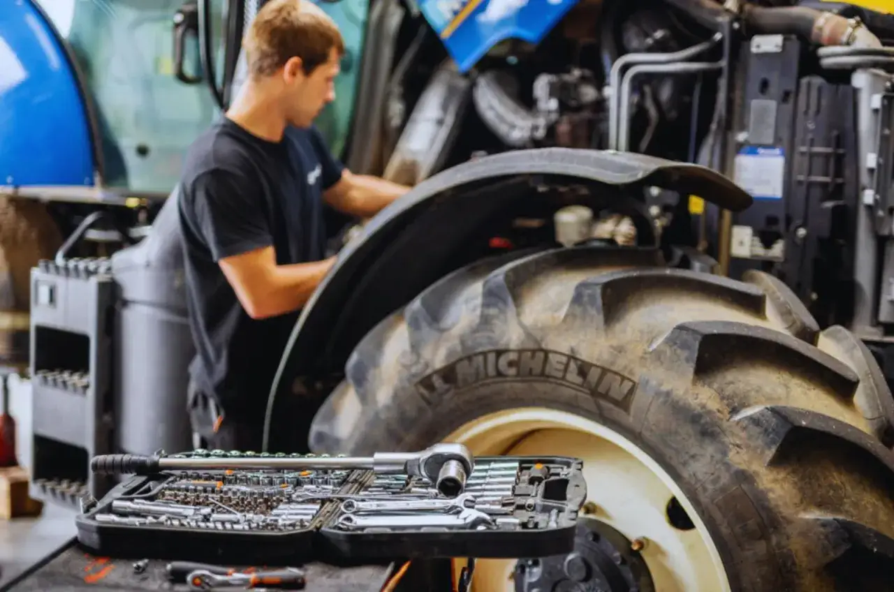 Mechanik pracuje przy traktorze, dbając o jego sprawność. Zestaw kluczy gotowy do akcji, zapewniający płynną eksploatację maszyn.