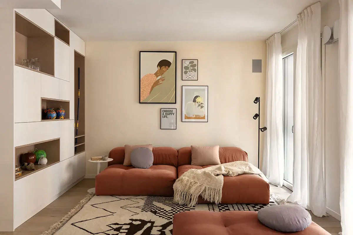 Un soggiorno moderno con divano color terracotta e un tappeto geometrico che si accosta a un altro tappeto a pelo lungo.