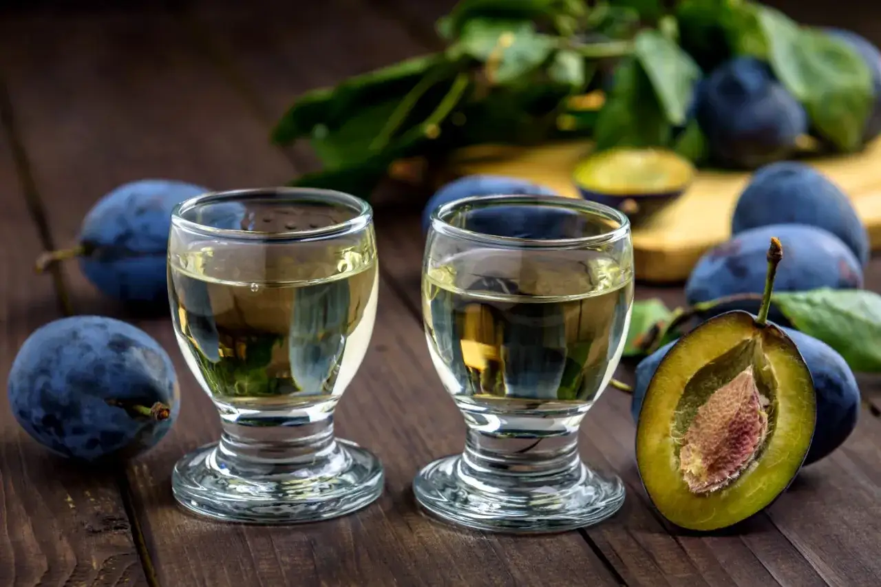 Dwa kieliszki domowej nalewki na whisky z suszonymi śliwkami, obok świeżych śliwek. Idealne na jesienne wieczory.