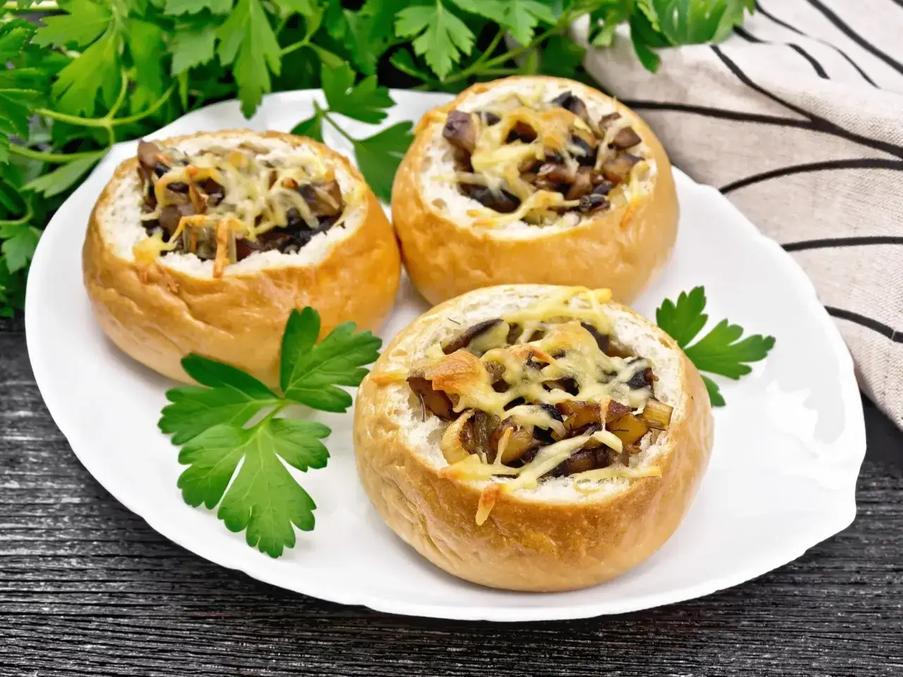 Pyszne zapiekanki z airfryer z pieczarkami i serem, podane na talerzu z natką pietruszki.