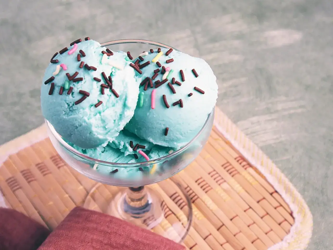 Ein Glas mit blauem Schlumpfeis, bestreut mit bunten Streuseln. Perfekt f&uuml;r ein einfaches Schlumpfeis Rezept.