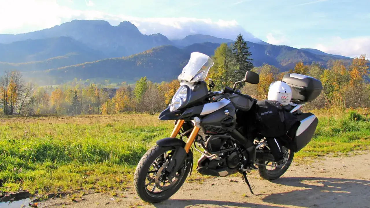 Motocykl gotowy na trasę motocyklową dookoła Polski. W tle jesienne krajobrazy i g&oacute;ry.