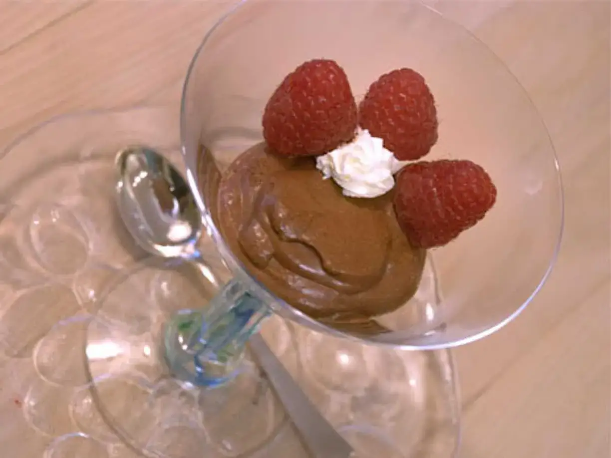 Enkel chokladmousse i ett glas med hallon och gr&auml;dde. En sked ligger bredvid.