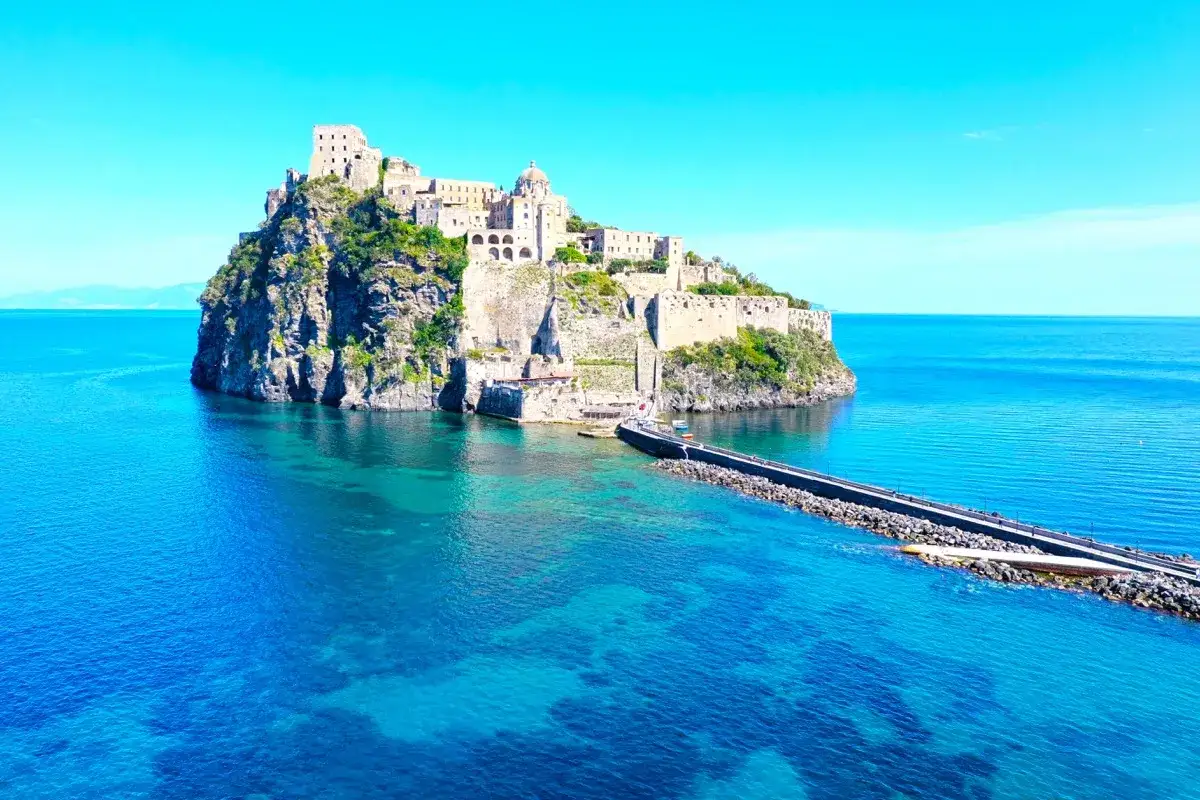 Castello Aragonese, simbolo di vittoria e storia a Ischia, si erge maestoso su uno scoglio, bagnato da un mare cristallino.