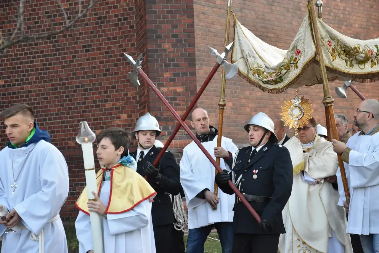 Uczestnicy procesji rezurekcyjnej niosą monstrancję i chorągwie.