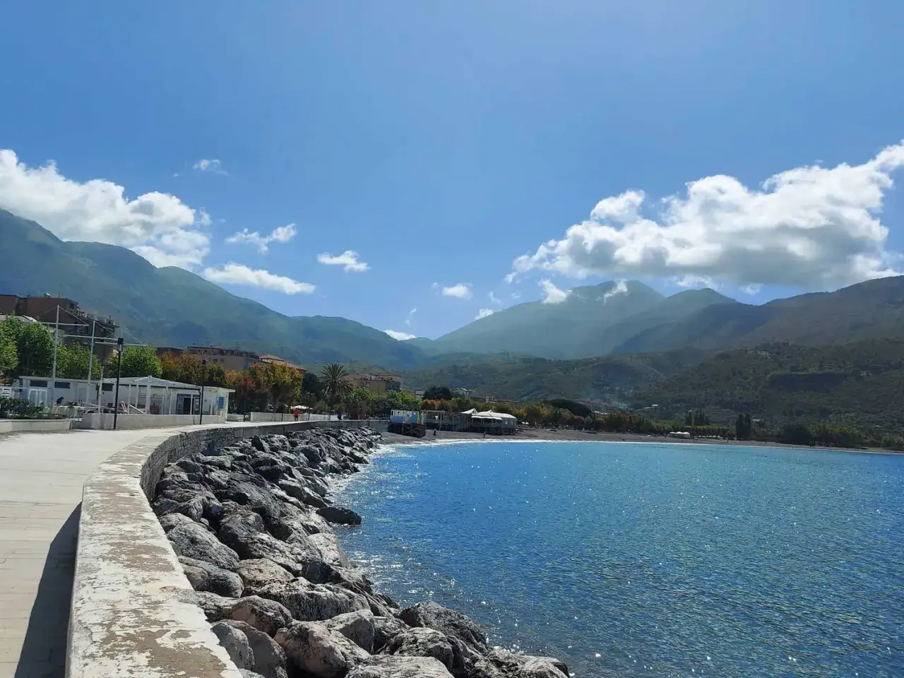 Passeggiata sul lungomare di Sapri, con rocce, mare blu e montagne verdi. Un luogo incantevole da scoprire.