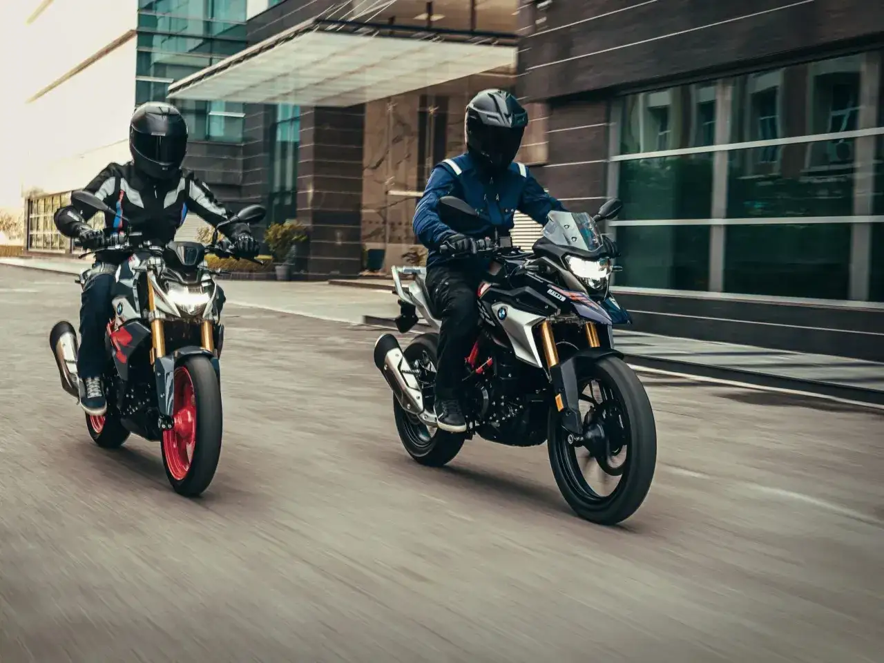 Dwóch motocyklistów na motocyklach BMW 310 przemierza miejską dżunglę.