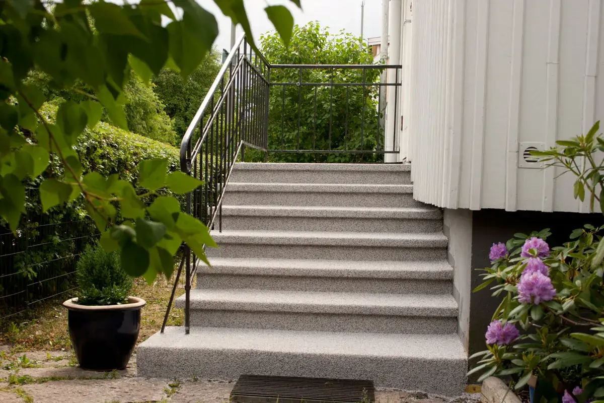 Nytt ytskikt på betongtrappa ger ett fräscht och hållbart resultat. En vacker entré med blommor och grönska.