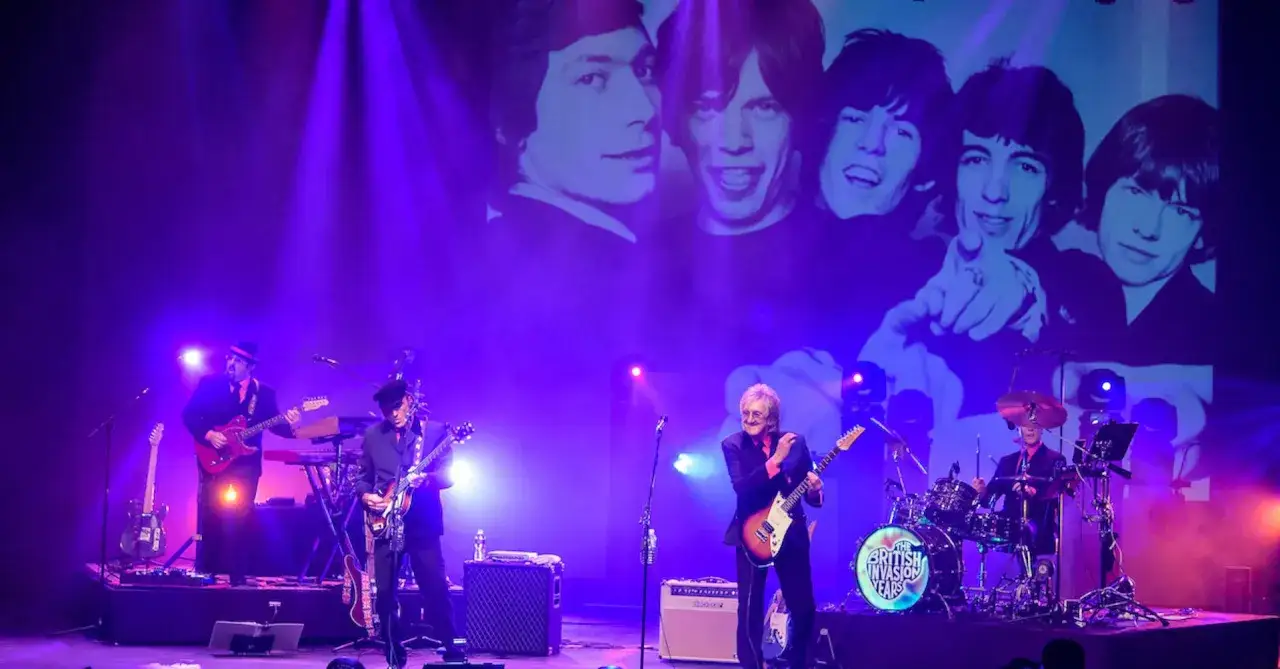 Le groupe rock anglais actuel The British Invasion Years sur scène, avec un écran projetant des photos iconiques.